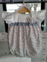 Pagliaccetto neonata Fiorellini Pagliaccetto per neonata - 100% cotone - con corpino e manichine ad aletta in tessuto sangallo, mutandina in tessuto fantasia fiorellini con decoro di volant in vita e fiore in tessuto applicato. Made in Italy