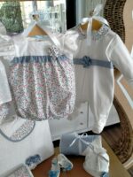 Pagliaccetto neonata Fiorellini Pagliaccetto per neonata - 100% cotone - con corpino e manichine ad aletta in tessuto sangallo, mutandina in tessuto fantasia fiorellini con decoro di volant in vita e fiore in tessuto applicato. Made in Italy