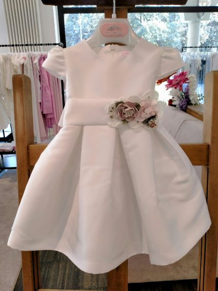 Abito Anemone Mimilù Abito neonata con manichine corte per Battesimo e cerimonia, confezionato in elegante tessuto mikado in tinta unita bianco e impreziosito dalla cintura regolabile in vita in raso con applicazione fiorata removibile, l'allacciatura posteriore ha la cerniera nascosta e grosso fiocco, la sottogonna è in cotone/tulle per rendere l'abito più ampio. Abito da Battesimo Abito da Cerimonia Neonata