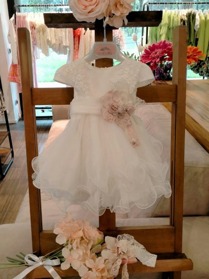 Abito Calla Mimilù Abito da cerimonia e Battesimo color latte, modello con manichine in misto cotone con gonna in tulle multistrato e ampia sottogonna, elegante corpino in pizzo debrodè, chiusura con zip invisibile sul retro. Nastro color latte in vita con applicazione floreale removibile e maxi fiocco sul retro. Abito da Battesimo Glam Abito da Cerimonia Neonata