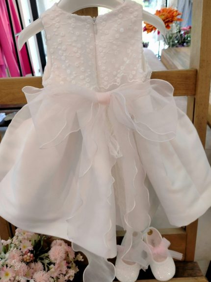 Abito Camelia Mimilù Abito da cerimonia e Battesimo color latte, modello senza maniche in mikado con ampia sottogonna ed elegante corpino ricamato applicato, cintura in organza color rosa tenue - annodabile sul retro con un grande fiocco e ampi lembi - completata da una raffinata spilla floreale rosa polvere e verde con dettagli in organza. Abito da Battesimo Glam Abito da Cerimonia Neonata