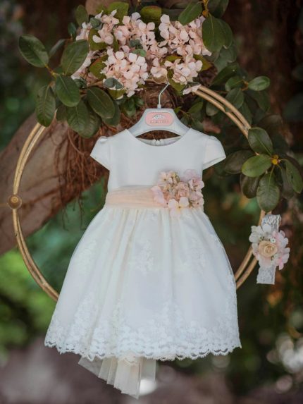 Abito Petunia Mimilù Abito da cerimonia e Battesimo color latte, modello con manichine corte, corpino in mikado, ampia gonna in elegante pizzo debrodè con doppia sottogonna in tulle/cotone, chiusura con zip invisibile sul retro. Nastro color rosa pesca in vita con applicazione floreale removibile e maxi fiocco annodabile con lembi sul retro. Abito da Battesimo Glam Abito da Cerimonia Neonata