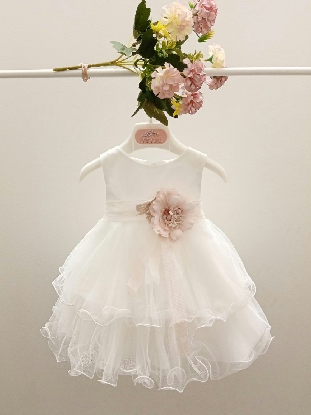 Abito Rosa Mimilù 302 Abito da Battesimo Abito da Cerimonia Neonata 00 Abito Rosa Mimilù Abito da cerimonia e Battesimo color latte, modello smanicato in misto cotone con gonna in tulle multistrato, ampio girocollo davanti e chiusura con zip invisibile sul retro. Nastro rosa in vita con applicazione floreale e maxi fiocco sul retro. Abito da Battesimo Abito da Cerimonia Neonata