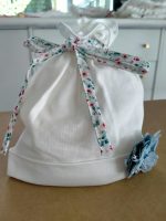 Cappellino neonata Fiorellini Cappellino in jersey di cotone con decoro fiore in tessuto. Made in Italy