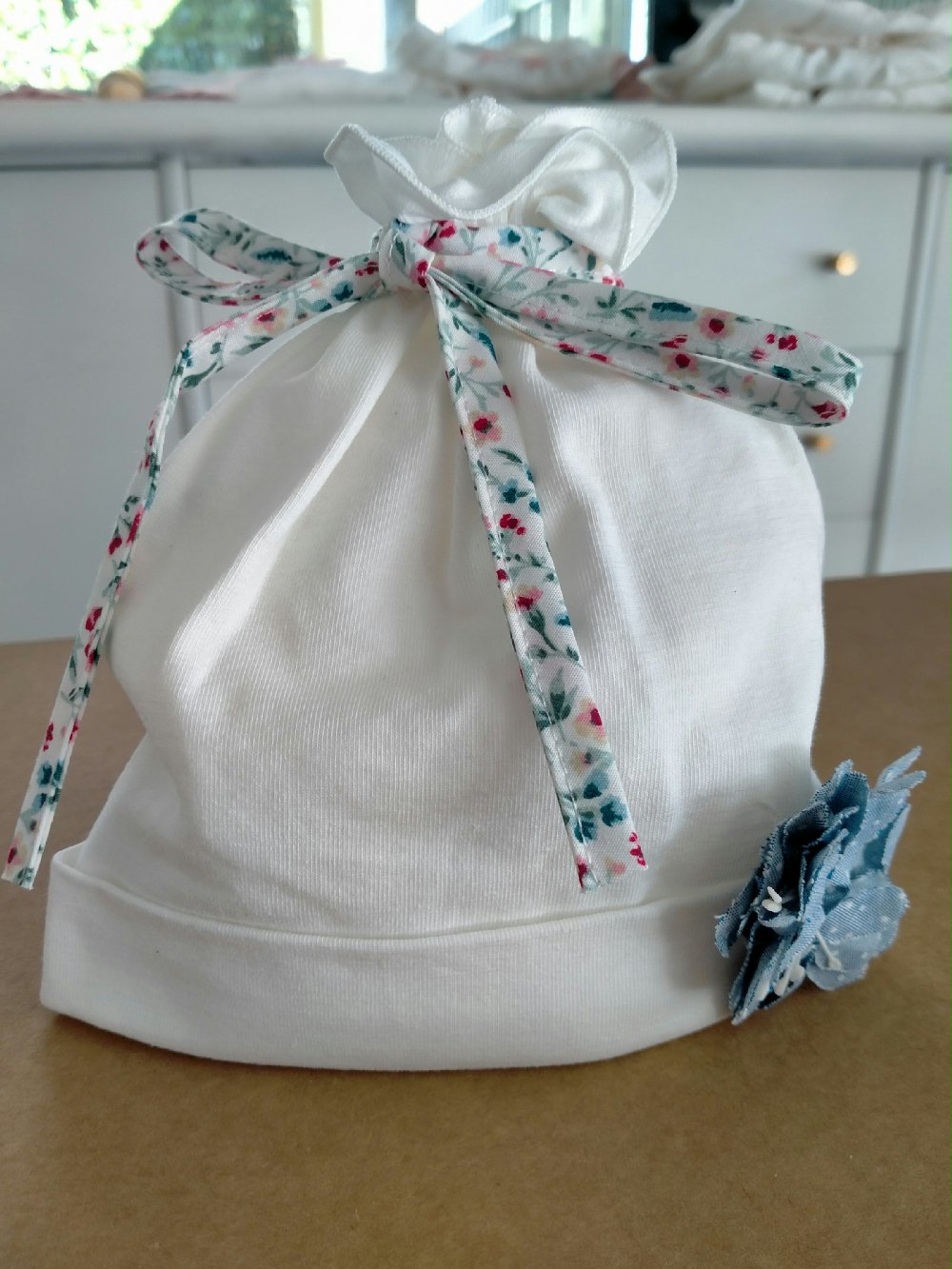 Cappellino neonata Fiorellini CA4740 00 Cappellino neonata Fiorellini Cappellino in jersey di cotone con decoro fiore in tessuto. Made in Italy