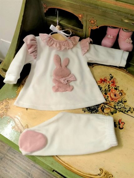 Completo due pezzi neonata Coniglietta Completo clinico due pezzi in ciniglia composto da: maglia color latte con colletto corolla in tessuto fantasia pois, volant in velluto al giromanica, applicazione frontale di un morbido coniglietto con fiocchetto, apertura dietro con bottoncini snap + ghettina color latte. Made in Italy Lista Nascita Corredino